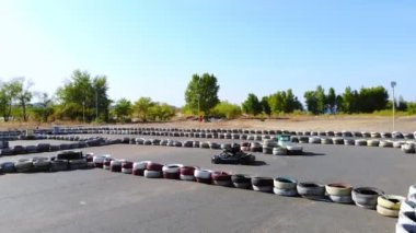Gençler açık havada araba yarışı yapıyor. Eski tekerleklerden yapılmış güvenlik bariyerleri var. On yaşında bir kız go-kart kullanıyor. Go-kart yarışı. Yaz