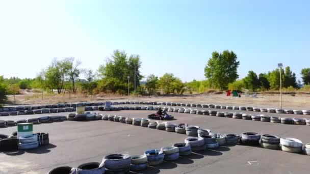 Jóvenes ir carrera de carros en circuito al aire libre. Hay barreras de seguridad hechas de ruedas viejas. Una niña de diez años conduce karts. Carreras de carros. Verano — Vídeo de stock