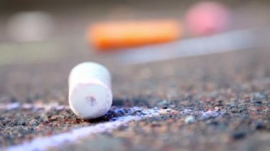 Yakın plan, renkli pastel boyalar asfaltta yatıyor.