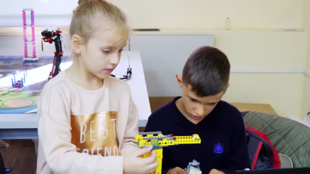 Crianças da escola, meninos e meninas, brincar com um designer de brinquedos, criar várias máquinas, robôs de designer de peças não-ferrosas, blocos coloridos. jogos educativos para crianças. construção — Vídeo de Stock