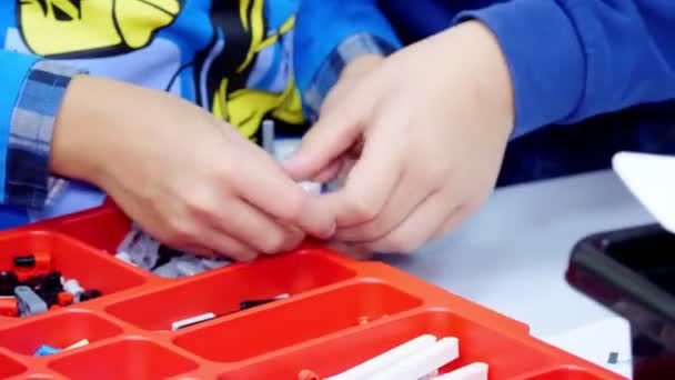 Primer plano, manos de los niños hacen algo con piezas de diseño. niños de la escuela crean varias máquinas, robots de piezas no ferrosas de diseño. Escuela de Robótica, educación STEM . — Vídeo de stock