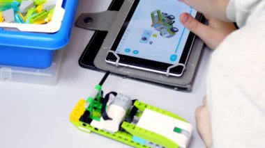 Yakın plan, tablet bir talimat gösteriyor, tasarımcıdan bir cihaz yaratmak için bir model. Okul çocukları, Robot Bilimleri ve Kök Eğitimi Okulu 'nda bir tasarımcıyla çalışıyor..