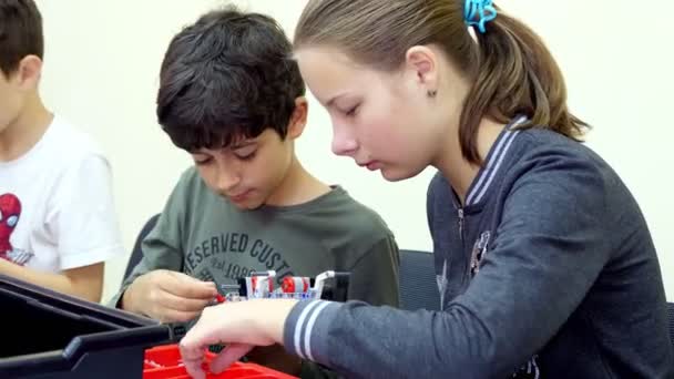 Школьники, мальчики и девочки, работают с дизайнером, создают различные машины, роботы из дизайнерских цветных деталей, блоки. Школа робототехники, STEM образование . — стоковое видео