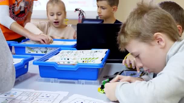 Okul çocukları, oğlanlar ve kızlar, bir tasarımcıyla çalışıyorlar, çeşitli makineler yapıyorlar, demirsiz parçalar tasarlayan robotlar, bloklar. Robot Bilimi Okulu, Kök Eğitimi. — Stok video