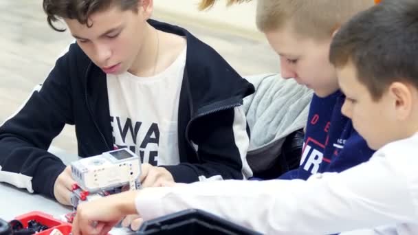 Students, children, boys and girls, create devices using the designer, non-ferrous parts, blocks, according to drawings in instructions on tablets. School of Robotics, STEM education. — ストック動画