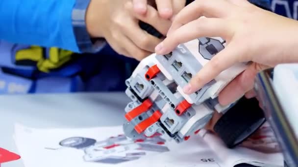 Primo piano, gli studenti creano un dispositivo utilizzando il progettista, parti non ferrose, blocchi, secondo i disegni nelle istruzioni. Scuola di Robotica, Educazione STEM . — Video Stock