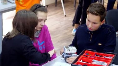 Öğrenciler, çocuklar, oğlanlar ve kızlar, tabletlerdeki çizimlere göre tasarımcı, demir olmayan parçalar, bloklar kullanarak cihazlar oluşturun. Robot Bilimi Okulu, Kök Eğitimi.
