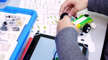 Yakın plan, öğrenci tabletteki çizimlere göre tasarımcıyı kullanarak cihaz, makine yaratıyor. Robot Bilimi Okulu, Kök Eğitimi
