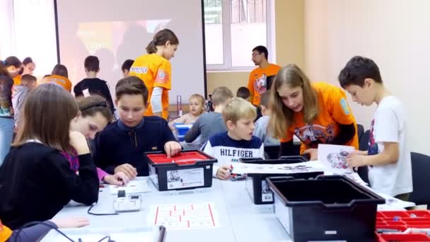 Czerkasy, Ukraina, 19 października 2019: studenci, dzieci, chłopcy i dziewczęta, tworzyć urządzenia przy użyciu projektanta, części nieżelazne, bloki, zgodnie z rysunkami w instrukcjach na tabletach. Szkoła — Wideo stockowe