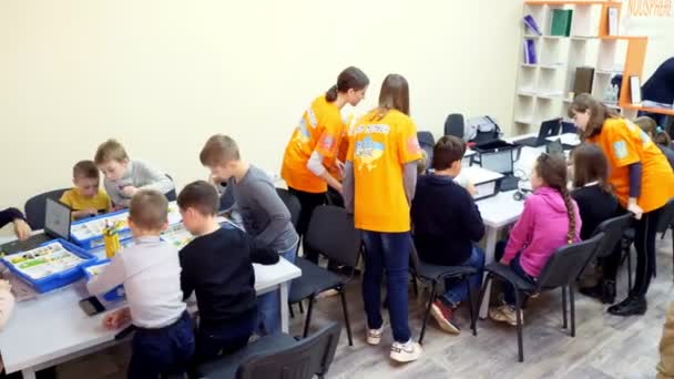 CHERKASY, UKRAINE, OCTOMBRIE 19, 2019: studenți, copii, băieți și fete, creează dispozitive folosind designerul, piesele neferoase, blocurile, conform desenelor din instrucțiunile de pe tablete. Școala de — Videoclip de stoc