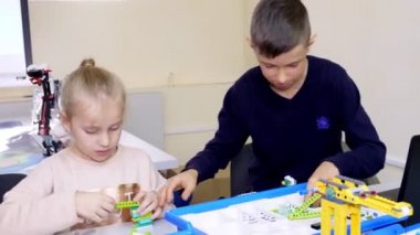 Öğrenciler, çocuklar, oğlanlar ve kızlar, talimatlara göre tasarımcı, demir olmayan parçalar, bloklar kullanarak cihazlar oluşturun. Robot Bilimi Okulu, Kök Eğitimi.