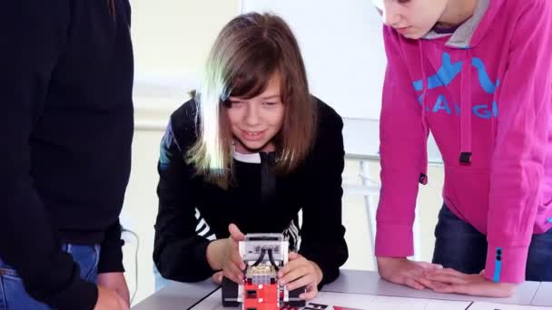 Menina brinca com um robô, máquina, feita de pequenos detalhes de designer. máquina se move, pode executar certas ações. lição educacional na escola de robótica, educação STEM — Vídeo de Stock