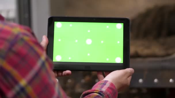 Närbild, bonden håller digital tablett med grön skärm i händerna, på bakgrund av potato lagring lager. jordbruk, livsmedelsindustri, skörd. — Stockvideo
