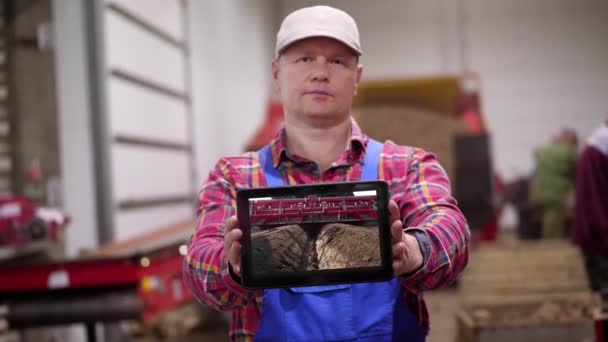 Boer houdt digitale tablet in handen op de achtergrond van aardappel opslag magazijn. Het toont cultivator geautomatiseerde aardappel planten. landbouw, levensmiddelenindustrie, oogst. — Stockvideo