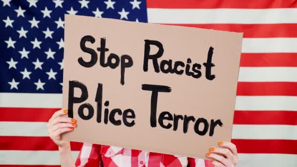 Protester har en banner med en slogan - Stop Racist Police Terror - mot bakgrund av den amerikanska flaggan. Kampen mot rasism, för lika rättigheter i USA. — Stockvideo