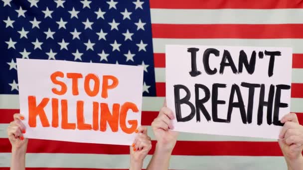 Протестующие держат плакаты с лозунгами - Прекратите убивать. I Cant Breathe - на фоне флага США. Борьба с расизмом, за равные права в США . — стоковое видео