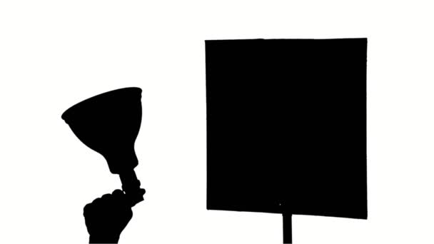 Primer plano, siluetas negras de megáfono y un cartel, manifestante los sostiene sobre fondo blanco. Activista en una protesta, mitin, manifestación — Vídeo de stock