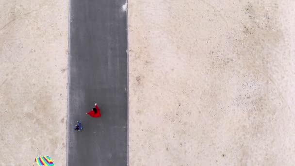 Havacılık. Üst Manzara. Bir kızla bir kadın, kumsalda gökyüzüne parlak, renkli bir gökkuşağı uçurtması uçuruyor. Güzel hava, bahar günü. Uçurtma fırlatılıyor. Eğlenceli açık hava aktivitesi. — Stok video