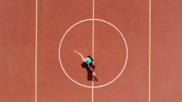 Aero, vedere de sus, Fitness femeie în îmbrăcăminte sport face diverse exerciții. fundal de teren de baschet portocaliu cu marcaje albe. Sporturi în aer liber. formare online. O zi de vară. Pe stadion — Videoclip de stoc