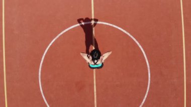 Aero, en iyi manzara, spor giyim sektöründe spor yapan kadın çeşitli egzersizler yapıyor. Beyaz işaretli turuncu basketbol sahasının arka planı. Açık hava sporları. Online eğitim. Yaz günü. Stadyumda.