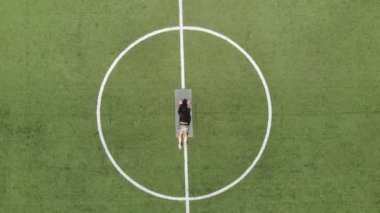 Aero, top view, spor giyimli kadın spor minder üzerinde çeşitli egzersizler yapıyor, yeşil futbol sahasında, stadyumda beyaz işaretli. Açık hava sporları. Online eğitim. Sıcak yaz günü. sağlıklı