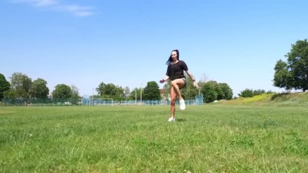 Mujer de fitness en ropa deportiva haciendo varios ejercicios sobre hierba verde del campo de deportes, en el estadio. Deportes al aire libre. formación en línea. caluroso día de verano. concepto de estilo de vida saludable — Vídeos de Stock