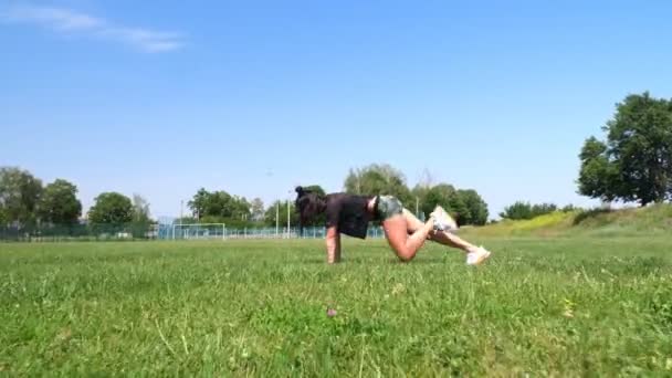 Kobieta fitness w odzieży sportowej robi różne ćwiczenia na zielonej trawie boiska sportowego, na stadionie. Sporty odkryte. szkolenie online. Gorący letni dzień. koncepcja zdrowego stylu życia — Wideo stockowe