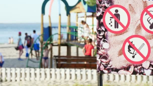 Nahaufnahme, Verbotsschilder auf dem Plakat, wie - nicht rauchen, nicht verschmutzen, nicht anzünden. auf dem Hintergrund des Spielplatzes. — Stockvideo