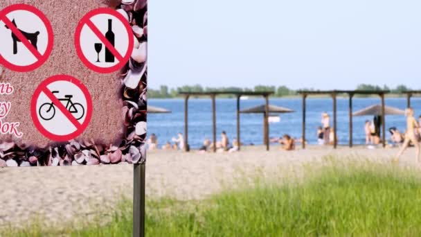 Крупним планом, забороняють знаки на плакаті, такі як - не п'ють алкоголь, не їздять на велосипеді, не ходять собаки. на фоні міського пляжу. спекотний літній день — стокове відео
