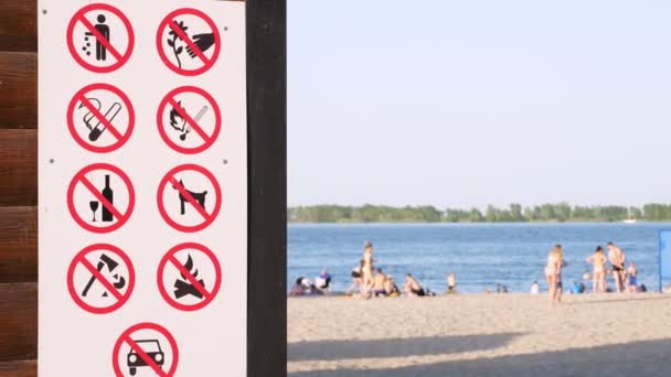 Yakın plan, posterlerde yasak levhalar, örneğin - çöp atmayın, sigara içmeyin, alkol almayın, ateş yakmayın, araba sürmeyin, köpekleri gezdirmeyin. Şehir plajının arka planı. sıcak yaz günü — Stok video