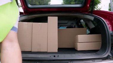 Yakın plan, erkek kurye paketleri boşaltıyor, bagajdan karton kutular, açık hava. Kargo teslimat servisi.