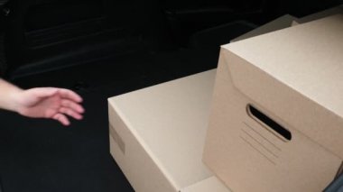 Yakın plan, karton kutular, kadın ve erkek eli. Kuryeler araba bagajından paketleri indiriyor. Kargo teslimat servisi..