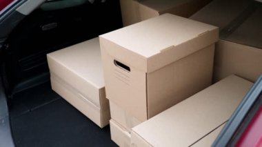 Yakın plan, erkek kurye, koruyucu maske, eldivenler, paketleri boşaltma, araba bagajındaki karton kutular. Kargo teslimat servisi karantina altında, koronavirüs salgını.