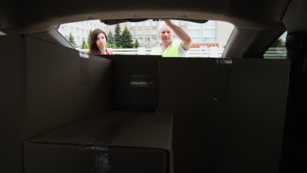 Vista desde el maletero del coche: Mensajeros, hombre y mujer, descarga de paquetes, cajas de cartón del maletero del coche. Servicio de entrega de carga . — Vídeos de Stock