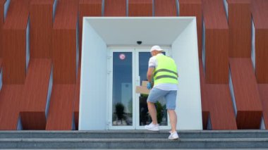 Coronavirüs salgını sırasında hastaneye tıbbi ekipmanla birlikte paket teslimatı. Kurye, koruyucu maskeli, eldivenli, giriş kapısında doktorun götürmesi için birkaç kutu bırakıyor..