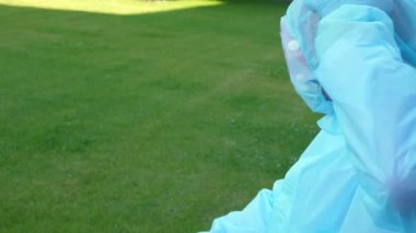 Yorgun ve yorgun doktor ya da hemşire koronavirüs koruyucu üniforma, maske, gözlük çıkarıyor. Dışarıda, hastanenin avlusunda ya da tıbbi tesiste. covid-19 salgını