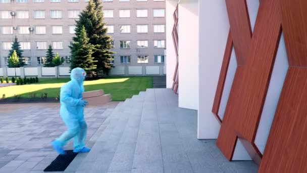 Levering van pakket met medische apparatuur of medicijnen aan het ziekenhuis tijdens de coronavirusuitbraak. Koerier, in beschermend pak, overhandigt kartonnen doos aan verpleegster. Vrachtvervoer tijdens quarantaine. — Stockvideo