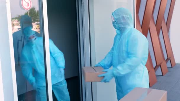 Coronavirus salgını sırasında hastaneye tıbbi ekipman ya da uyuşturucu taşıyan paket teslimatı. Kurye, koruyucu kıyafetli, hemşireye karton kutular veriyor. Kargo teslimat servisi karantina sırasında. — Stok video