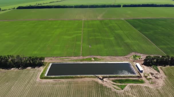 Aero. Ansicht von oben. künstlich hergestelltes Spezialbecken, Wasserspeicher, Tank oder Reservoir für die Bewässerung landwirtschaftlicher Felder. In der Nähe befindet sich eine Pumpstation für die Wasseraufnahme. moderne Technologien in der Landwirtschaft. — Stockvideo