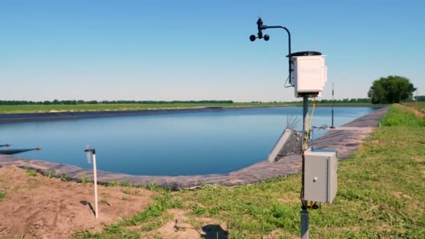 Instrument meteorologiczny. Mała stacja meteorologiczna na polu uprawnym, niedaleko zbiornika nawadniającego. Koncepcja inteligentnej technologii rolniczej — Wideo stockowe