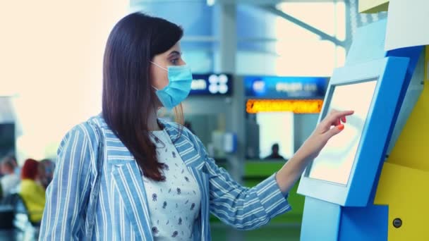 Primer plano, una joven se registra en el quiosco de auto check-in en el aeropuerto. apertura de los viajes aéreos tras la pandemia de coronavirus. — Vídeo de stock