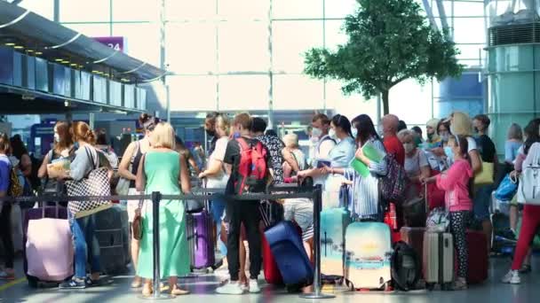 BORISPYL, UKRAINE, JULI 31, 2020: op de luchthaven, mensen met beschermende maskers, met bagage, in de rij staan voor de incheckbalies, geen veilige afstand bewaren. — Stockvideo