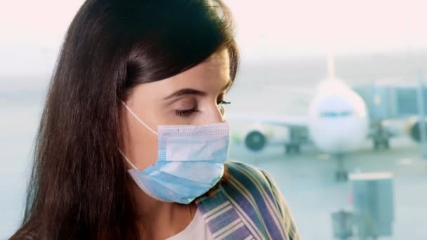 Maskeli kadın portresi, panoramik pencerenin önünde, uçak manzaralı, havaalanında. Coronavirüs salgını bittikten sonra uçuşlar yeniden başladı. Sınırlar açılıyor. seyahat açık — Stok video
