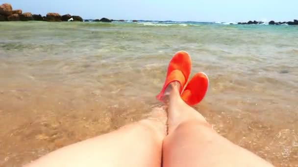 Nahaufnahme, weibliche Beine in leuchtend orangefarbenen Wasserschuhen, zum Schwimmen im Meer, um sich an den Riffen nicht zu verletzen. Konzept für den Urlaub am Meer — Stockvideo