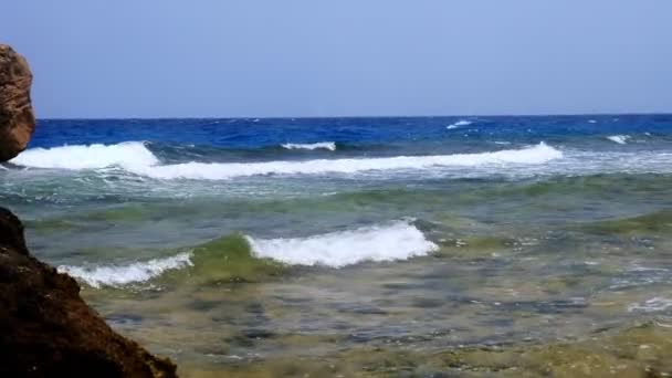 Bela paisagem marinha. ondas de surf pequenas com espuma branca, quebrando na praia rochosa do Mar Vermelho. paisagem marinha cênica de verão, vista pitoresca da costa ensolarada . — Vídeo de Stock