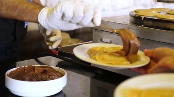 Primer plano, un camarero en guantes de protección sirve crema de chocolate a los panqueques. nuevas reglas de servicio en restaurantes todo incluido gracias a covid-19 — Vídeo de stock