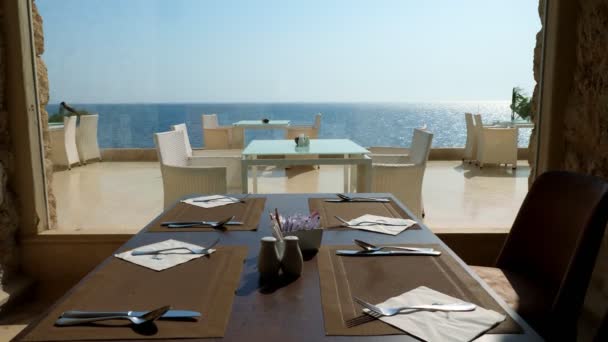 Table servie dans le restaurant par une grande fenêtre panoramique donnant sur la mer. — Video