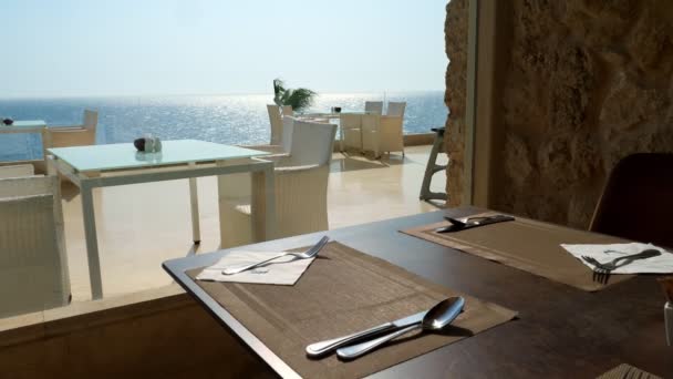 Geserveerd tafel in het restaurant door een groot panoramisch raam met uitzicht op de zee. — Stockvideo