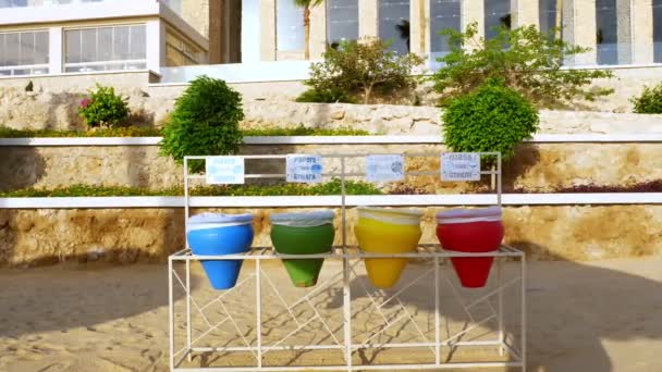 Різнокольорові сміттєві баки, для сортування відходів, на пляжі . — стокове відео