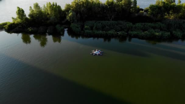 Luchtvaart. groep vrouwen die SUP yoga beoefenen, balanceren ze op peddelplanken, op water van de grote rivier, tijdens de zomerse warme zonsondergang. borden worden in cirkel weergegeven, in de vorm van een bloem. SUP yoga training - — Stockvideo